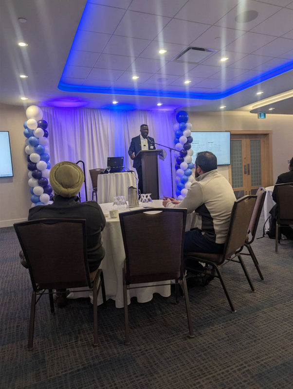Ev Oputa presenting from a podium to a seated room